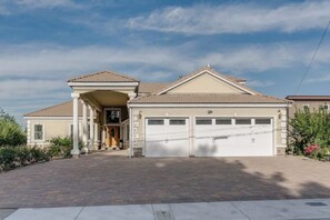 A two-story house with a covered porch, a garage with two doors, and a paved driveway. - Spacious Upscale Home in Central Reno (Reno)