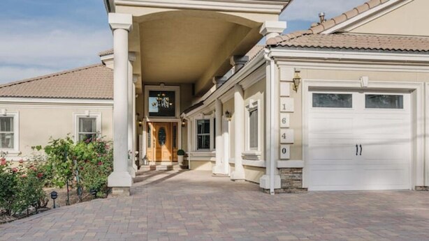 A two-story house with a covered front porch, a garage, and a brick driveway.