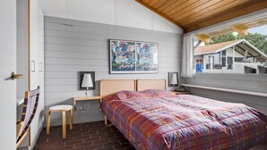 A bedroom with a large bed, a desk, a chair, a window with a view of a house, and a painting on the wall. - 2 bedroom amazing home in Aabenraa (Aabenraa)