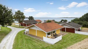 A coastal property with a yellow house, a red garage, and a white fence. - 2 bedroom amazing home in Aabenraa (Aabenraa)
