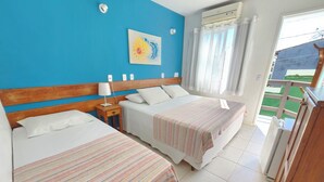 A hotel room with two beds, a blue wall, a painting, an air conditioning unit, and a view of a green area outside. - Pousada Anambé (Angra dos Reis)