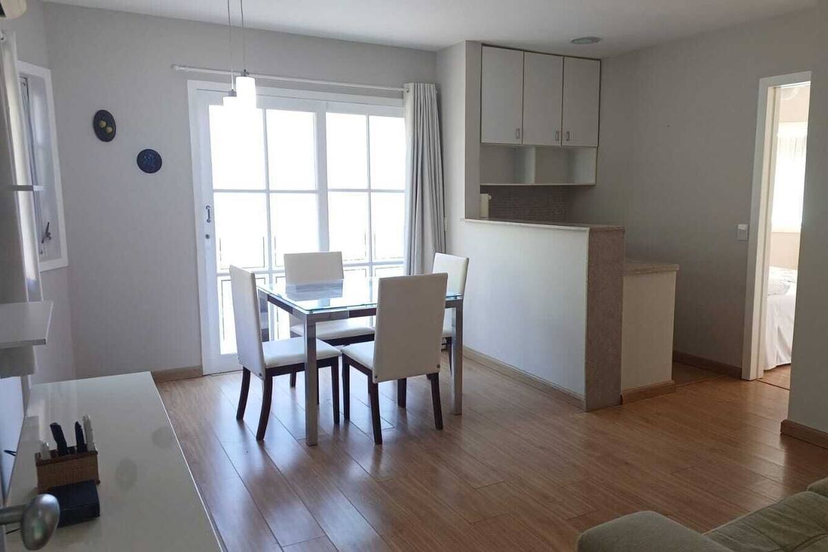 A modern apartment with a dining area, kitchenette, and a living room.