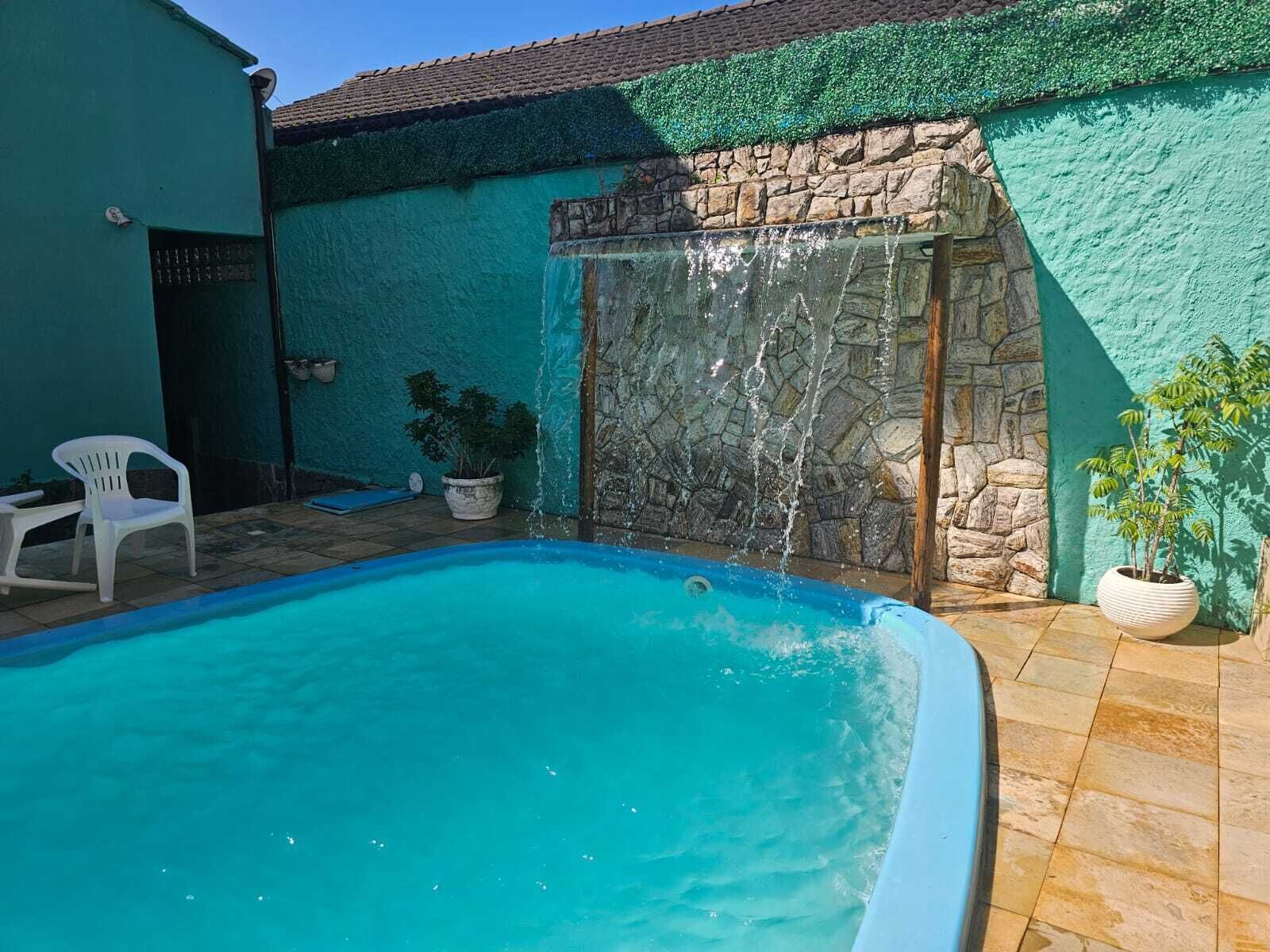 A swimming pool with a stone wall and a small waterfall feature.