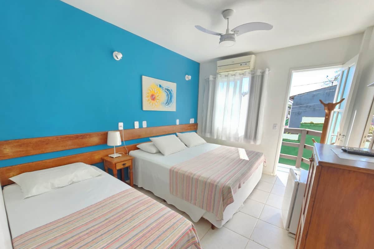 A hotel room with two beds, a ceiling fan, an air conditioning unit, and a view of the outside.