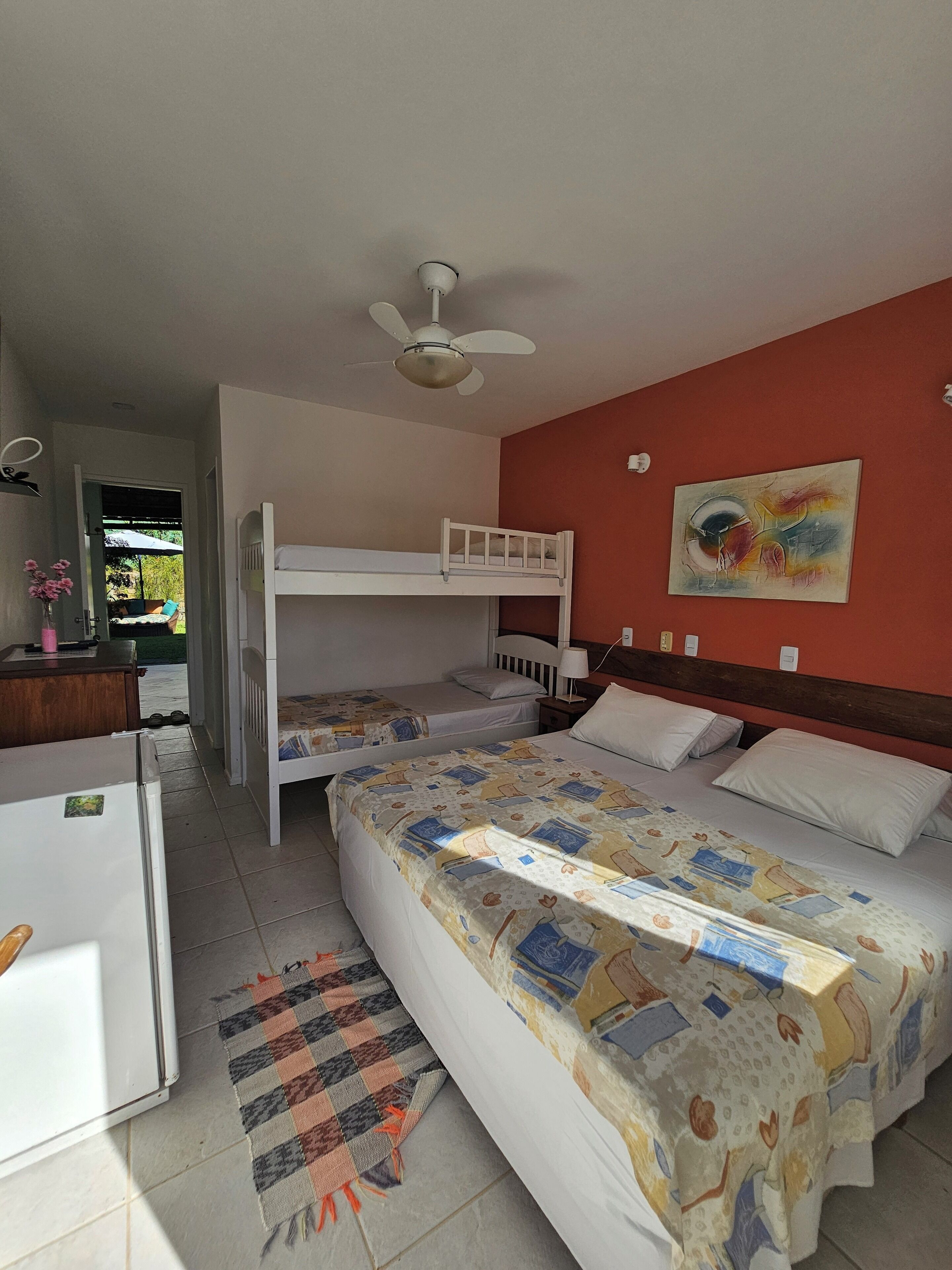 Una habitació amb llits superposats, un ventilador de sostre, un quadre a la paret i un escriptori amb nevera.