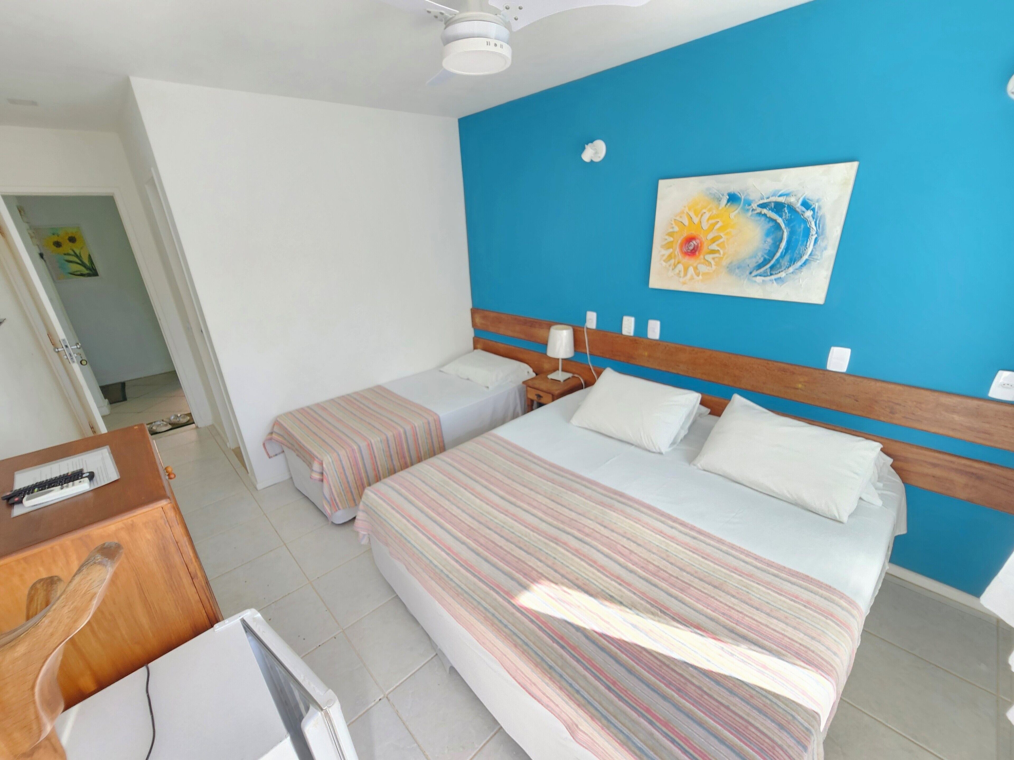 A hotel room with two beds, a desk, and a ceiling fan.