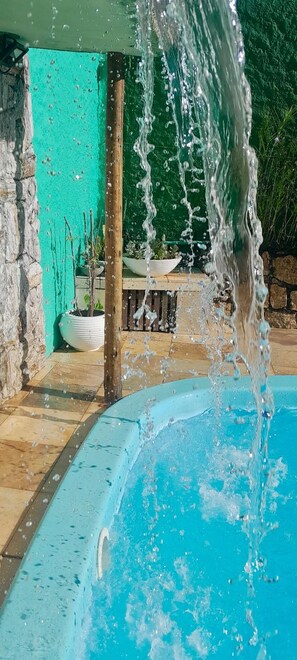 A swimming pool with clear blue water and a waterfall feature. - Pousada Anambé (Angra dos Reis)