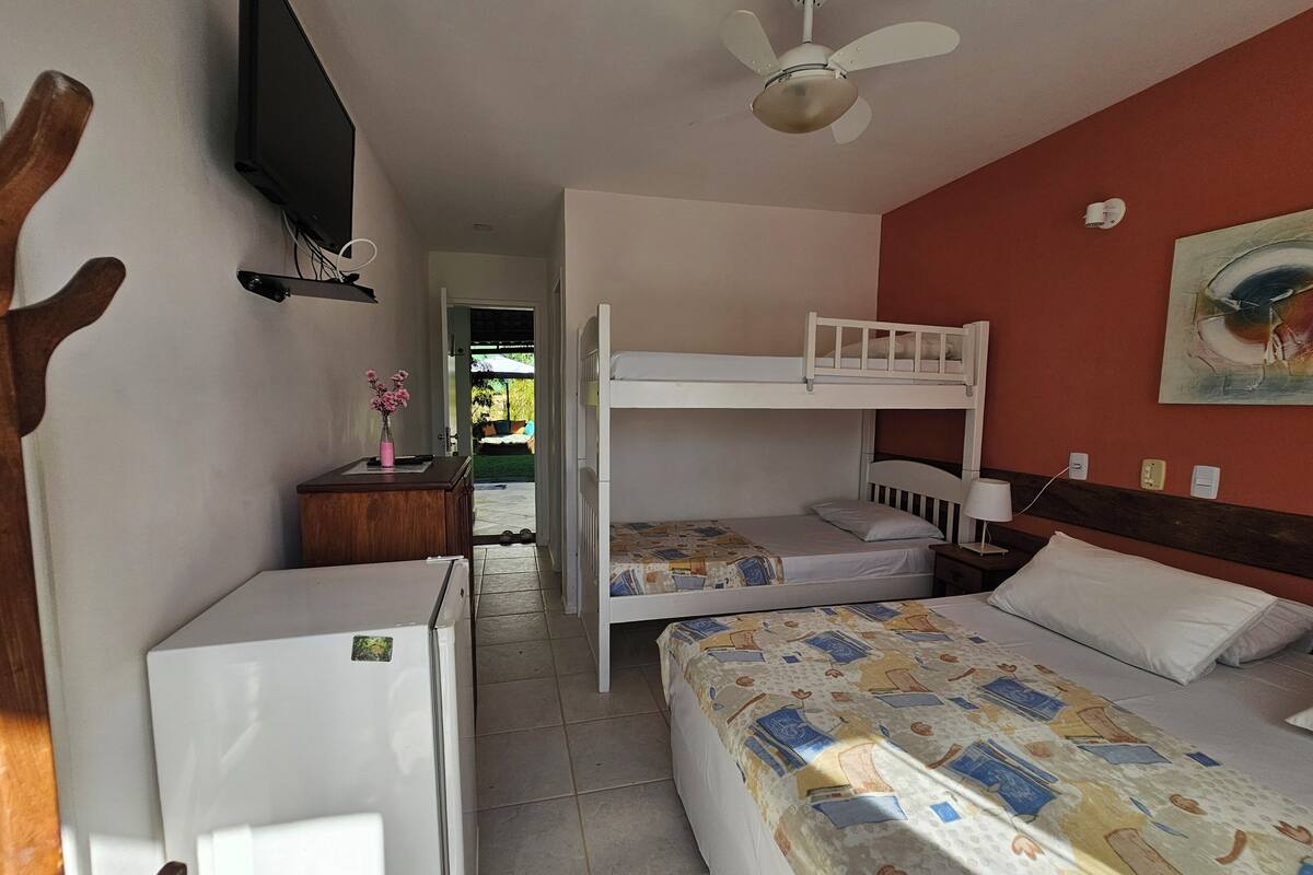 A room with bunk beds, a desk, a television mounted on the wall, and a ceiling fan.