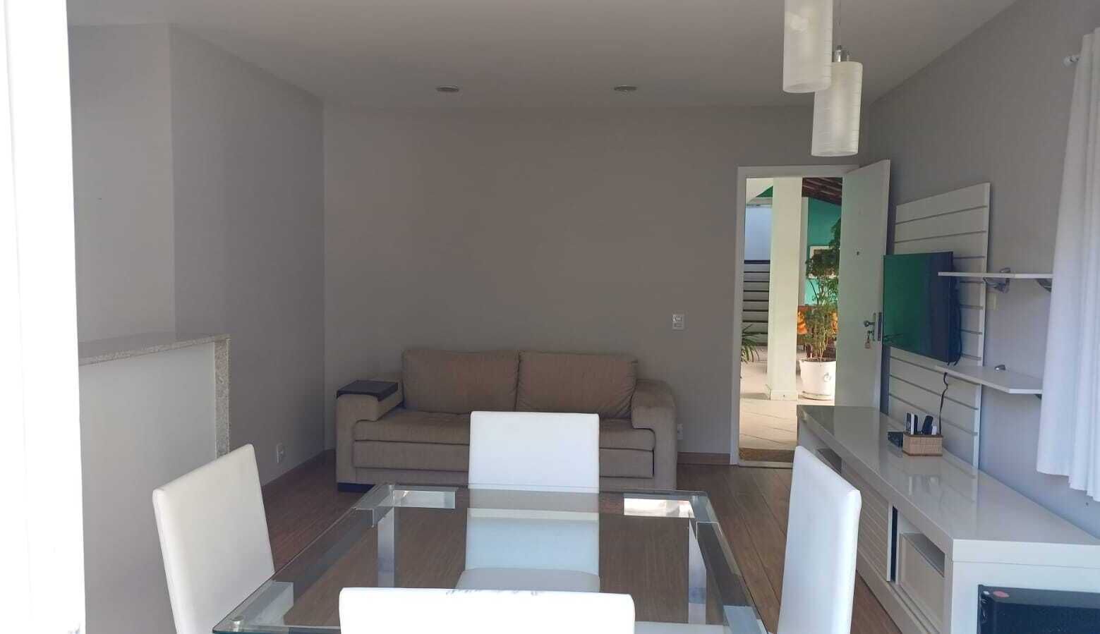 A modern living room with a glass coffee table, a beige sofa, and a white TV stand.
