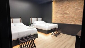 Ein modernes Schlafzimmer mit zwei Betten, einer Ziegelwand und einem Holzboden.