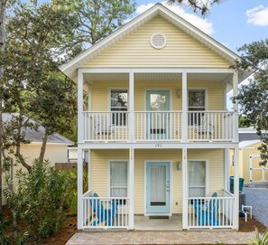 A two-story building with a light yellow exterior, a balcony on each floor, and a blue door.