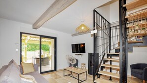 A modern living room with a sofa, a coffee table, a TV, and a staircase with a unique design.