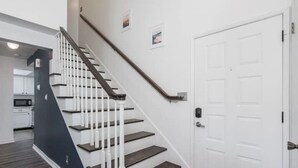 Eine Treppe mit weißen Geländern und dunklen Stufen, die zu einer weißen Tür führt.