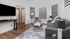 Een moderne woonkamer met een flatscreen televisie, een bank, een salontafel en een plafondventilator.