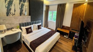 A modern hotel room with a large bed, a desk with a lamp, a telephone, and a television. - Wishotel Inn Rasa Royal - A Boutique Hotel (Indore)