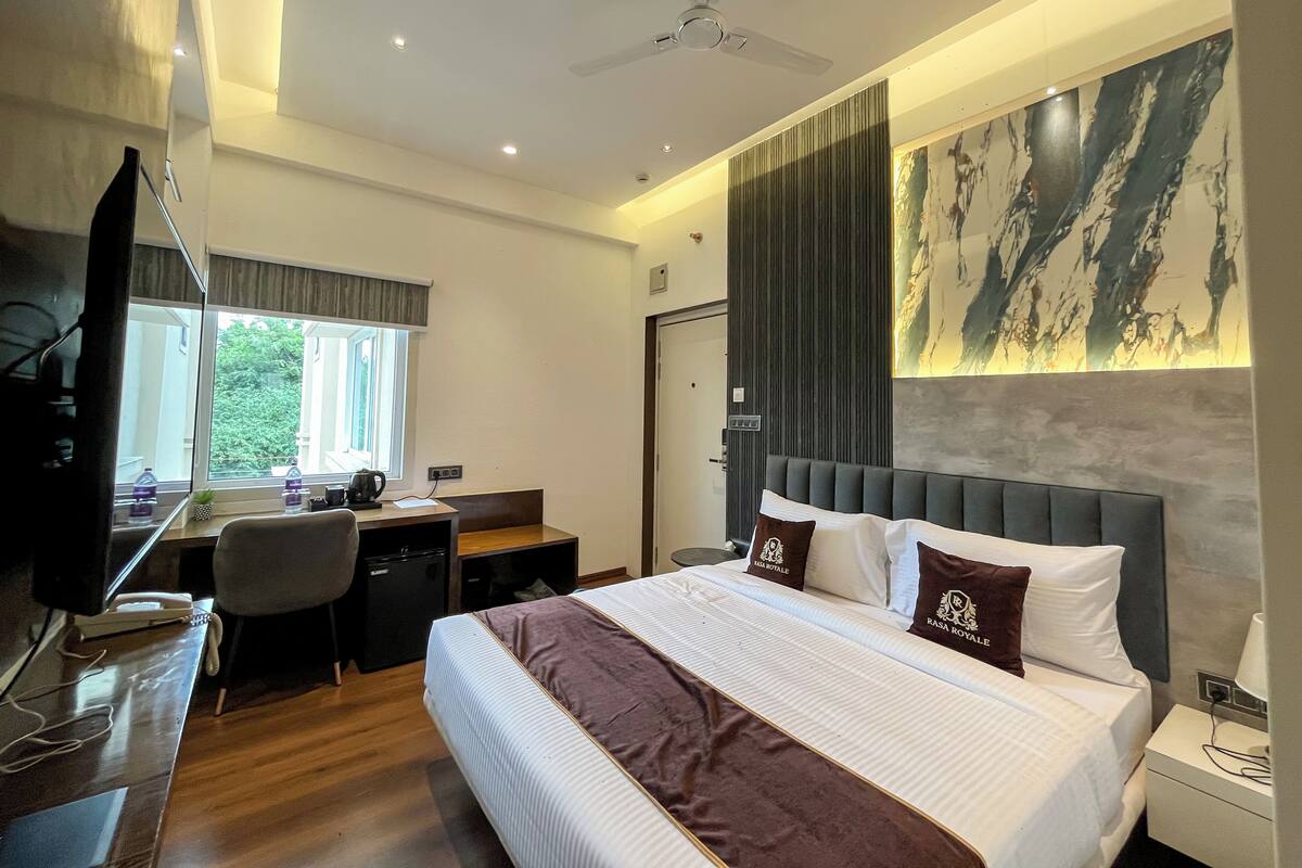Une chambre d’hôtel équipée d’un lit, d’un bureau, d’une chaise et d’un téléviseur.