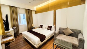 A hotel room with a bed, a desk, a sofa, and a glass coffee table. - Wishotel Inn Rasa Royal - A Boutique Hotel (Indore)