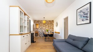 A modern kitchen with white cabinetry, a stone accent wall, and a dining area with a table and chairs. - 2 bedroom beautiful home in Starigrad (Starigrad)