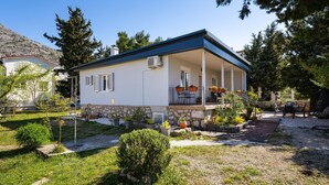 A two-story house with a covered porch, stone foundation, and a small garden area. - 2 bedroom beautiful home in Starigrad (Starigrad)