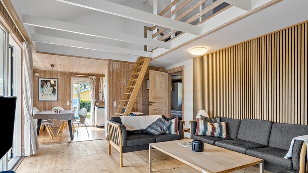 Un salon moderne avec un plancher en bois, un canapé, une table basse et un escalier menant à un niveau supérieur.