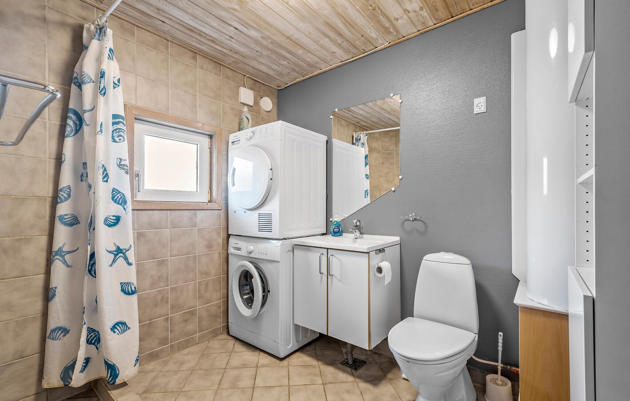 A small, compact bathroom with a washing machine, a toilet, and a sink.