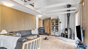 Un salon moderne comprenant un canapé, un fauteuil, une table basse, une cheminée et un téléviseur.