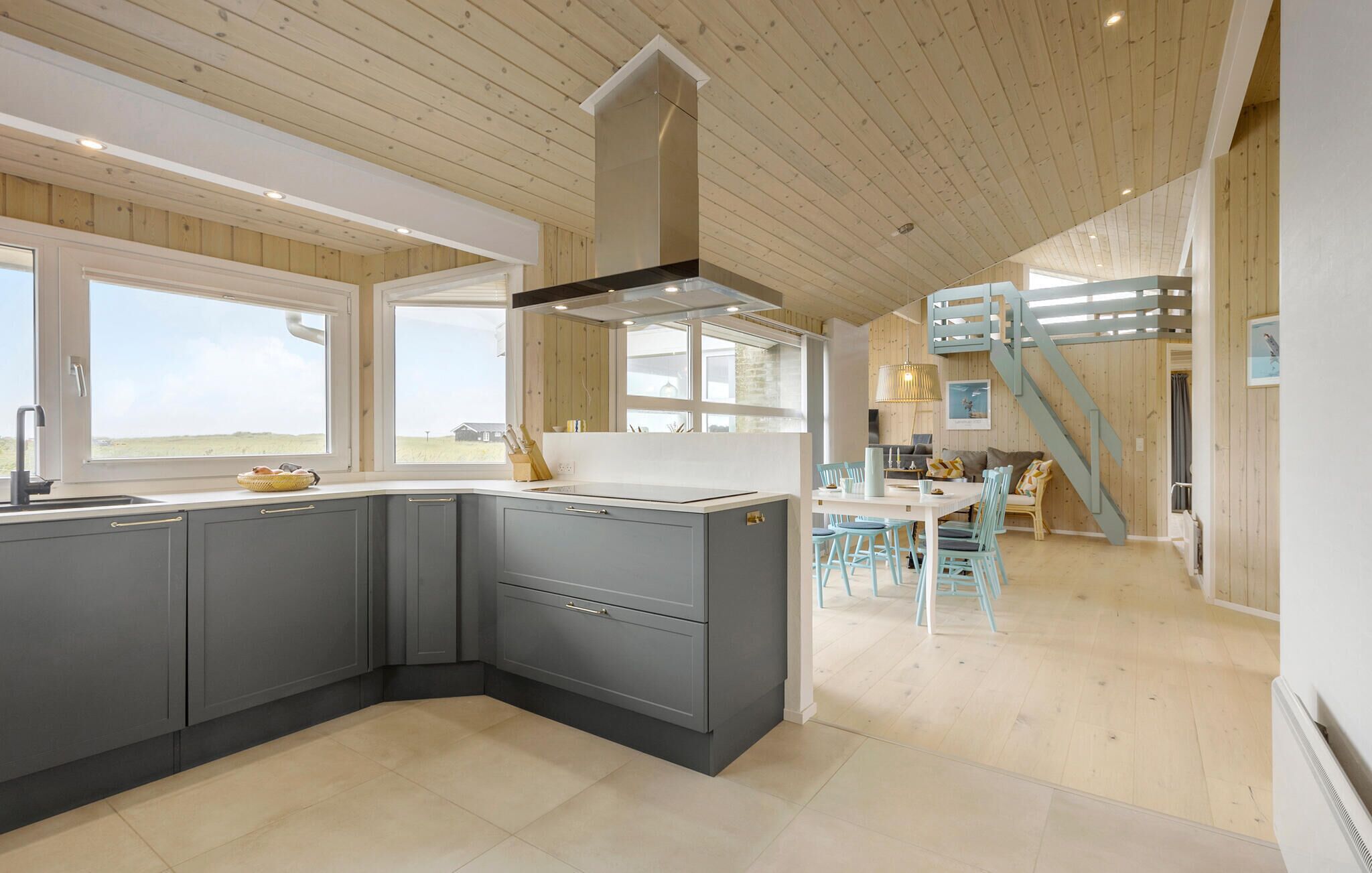 Une cuisine moderne avec des meubles gris, un îlot central et une vue sur la campagne.