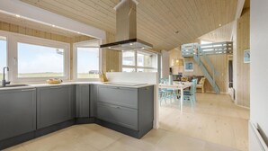 A modern kitchen with grey cabinets, a central island, and a view of the countryside. - 3 bedroom ocean front home in Hjørring (Hjørring)