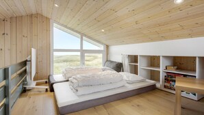 A bedroom with a large window, a bed, a desk, and built-in shelves. - 3 bedroom ocean front home in Hjørring (Hjørring)