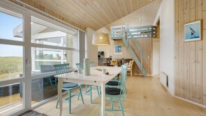 A spacious room with a large table and chairs, a staircase, and a view of the outdoors. - 3 bedroom ocean front home in Hjørring (Hjørring)