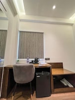 Un espacio de trabajo compacto con escritorio, silla y un pequeño refrigerador negro.