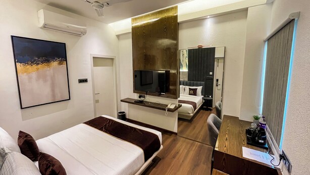 A modern hotel room with a bed, a desk, a TV, and a bathroom visible through an open door. - Wishotel Premier Parth Residency (Deoria)