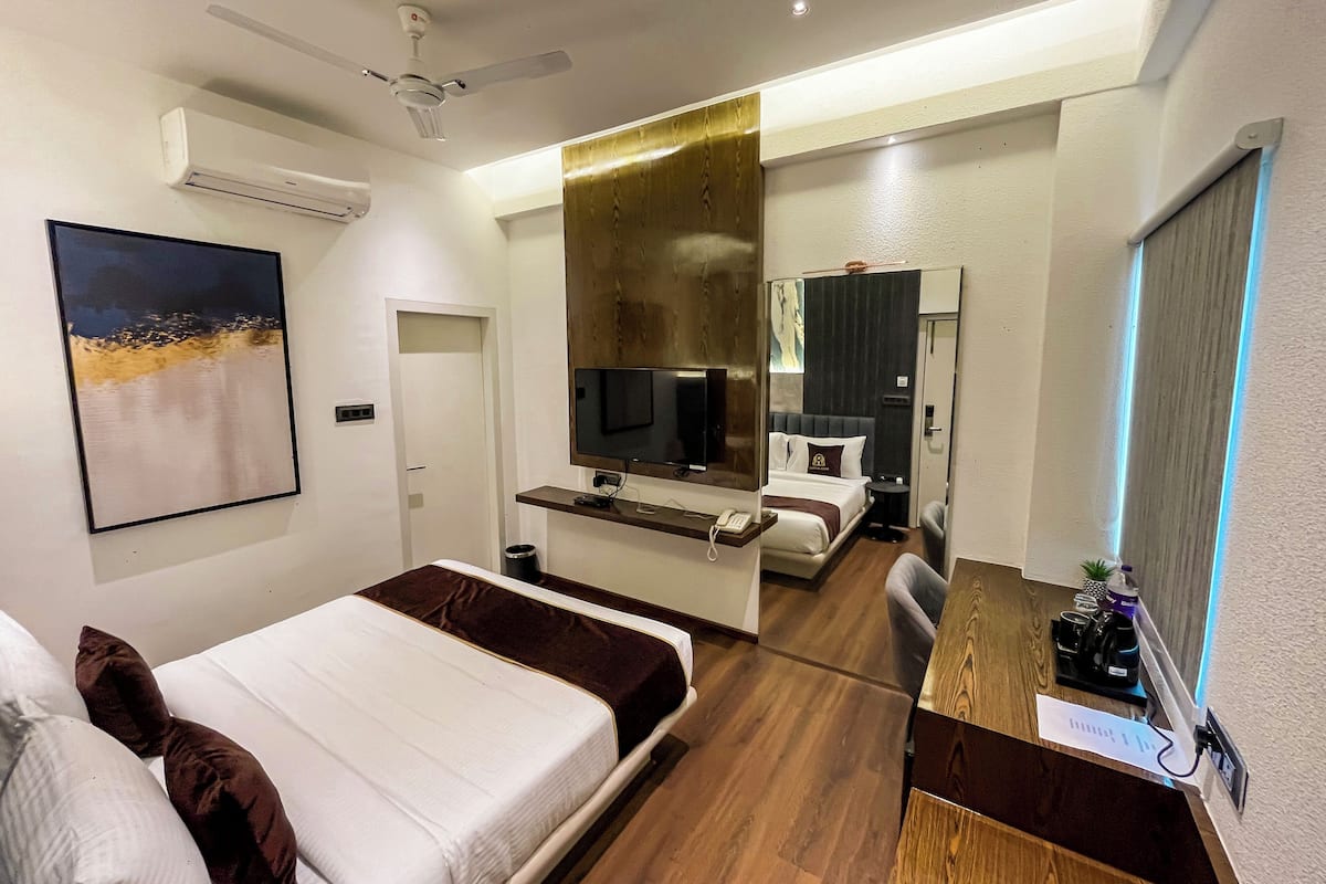 A modern hotel room with a bed, a desk, a TV, and a bathroom visible through an open door.