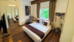 A modern hotel room with a large bed, a desk, a chair, a TV, and a window with curtains. - Wishotel Premier Parth Residency (Deoria)