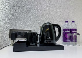 Una cafetera, dos botellas de agua Bailey y dos vasos sobre una mesa.