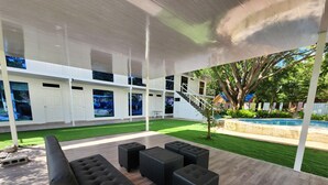 An outdoor seating area with a modern design, featuring a wooden deck and black cushioned seating.