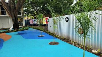 A pathway with blue pavement, potted plants, and a corrugated metal fence.
