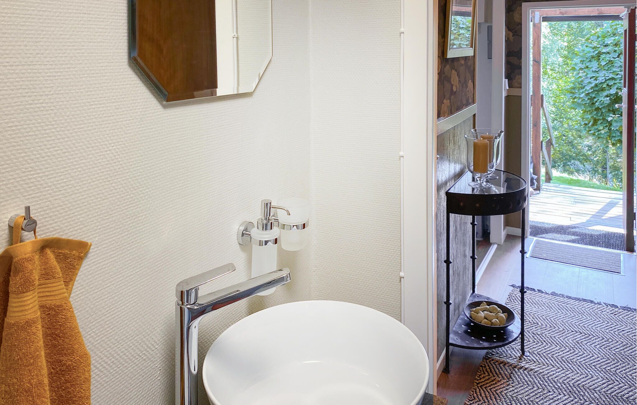 Une salle de bain avec un lavabo blanc, des robinetteries chromées, un porte-serviettes et un miroir.