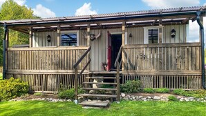 A rustic wooden cabin with a porch, a staircase leading to the entrance, and a small garden area with rocks and plants. - Nice home in Sävsjö with WiFi (Sävsjö)