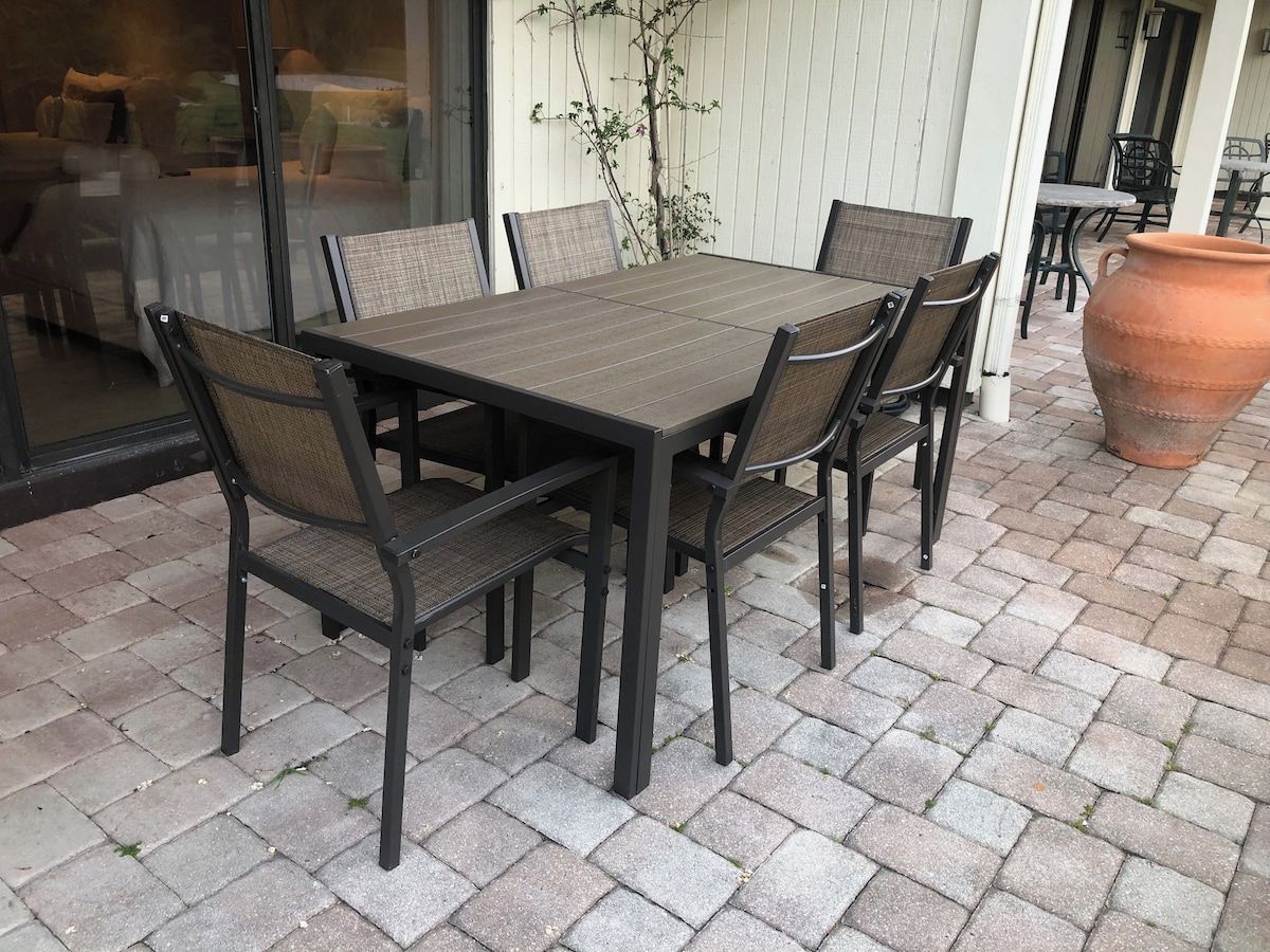 Un patio exterior con una mesa rectangular y seis sillas.