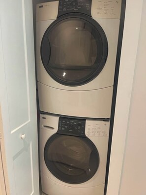 A stacked washer and dryer unit with control panels and labels.