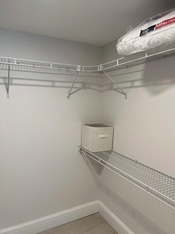 A corner closet with wire shelving units, a storage box, and a bag on the top shelf.