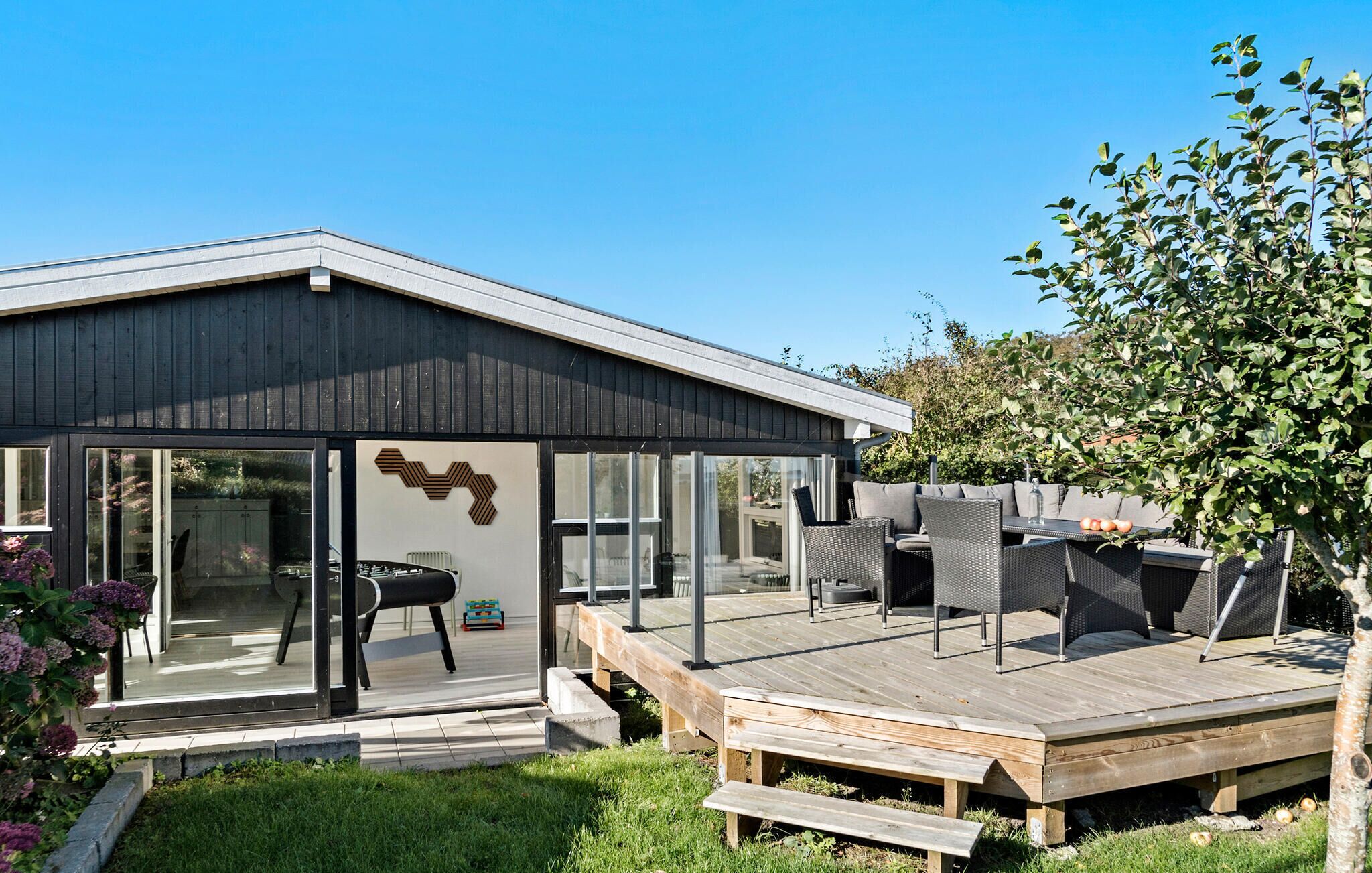 Een modern huis met een terras, zitplaatsen buiten en een tuin.