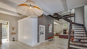 Un intérieur spacieux avec un plafond haut, un escalier et un grand luminaire.