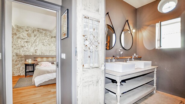 Une salle de bain moderne avec deux lavabos, un miroir et un espace douche.