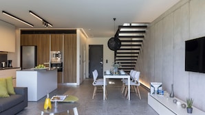 Un espacio habitable moderno con cocina, comedor y una escalera.