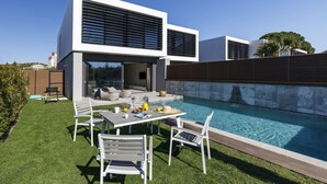 Una casa moderna con piscina, mobiliario exterior y un césped bien cuidado.