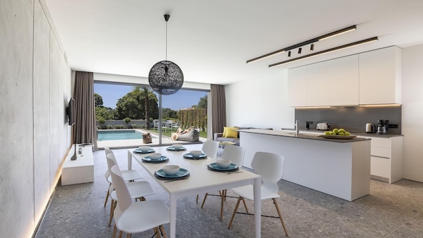 Una cocina moderna con comedor, un ventanal con vista a una piscina y vegetación.