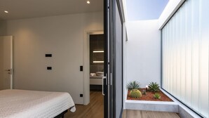 Un dormitorio moderno con cama, vestidor y un pequeño balcón con plantas.