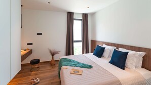 Een moderne hotelkamer met een groot bed, een zithoekje en een raam met gordijnen.